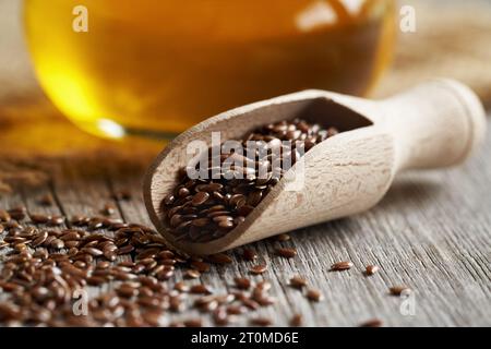 Leinsamen auf einem Holzlöffel, mit einer Flasche Leinöl im Hintergrund Stockfoto
