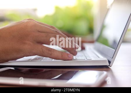 Nahaufnahme des Tippens männlicher Hand auf der Laptop-Tastatur. Freiberuflich im Café arbeiten und die Umgebung genießen Stockfoto