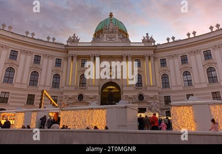 WIEN, Österreich - 6. Januar 2023: Schloss Hofburg an einem Weihnachtsabend mit geschmückten Ständen neben dem Eingang voller Menschen Stockfoto