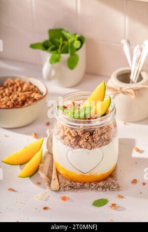 Hausgemachtes und köstliches Mangogranola aus frischen Zutaten. Sommerfrühstück mit Mango und Joghurt. Stockfoto