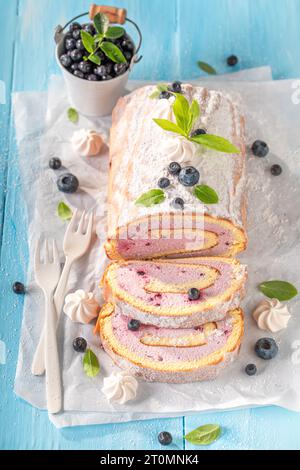 Süße Heidelbeere schweizer Roulette als Frühlingsdessert. Mango schweizer Brötchen mit Beeren und Zucker. Stockfoto