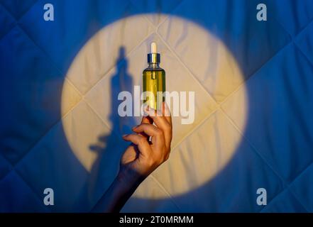 Frau Hand auf dem Hintergrund einer Decke im Licht des Mondes mit Tropfer mit Schlaföl. Schlaflosigkeit bekämpfen Stockfoto