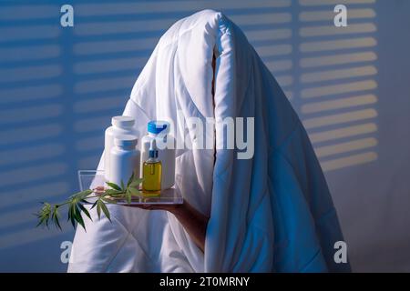 Finden Sie Ruhe: Mädchen kämpft Schlaflosigkeit unter Trusty Blanket mit Schlaffkapsel mit einem Cannabiszweig der Nachtstation mit Blinden Stockfoto