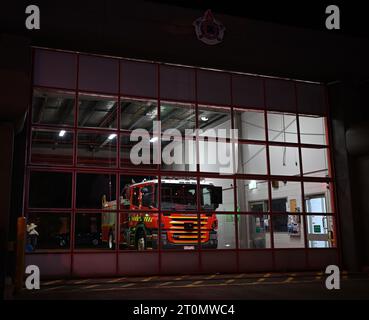 Außenansicht der Feuerwehr Victoria Fire Station 32 bei nächtlicher Beleuchtung, mit rotem Scania P 320 Lkw mit FRV-Lackierung im Inneren Stockfoto