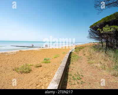 Vormittag am Strand von Bibione in italien, Sanddünen und steinige Wellenbrecher in der Nähe des Leuchtturms von Bibione, erbaut im Jahr 1913. Stockfoto