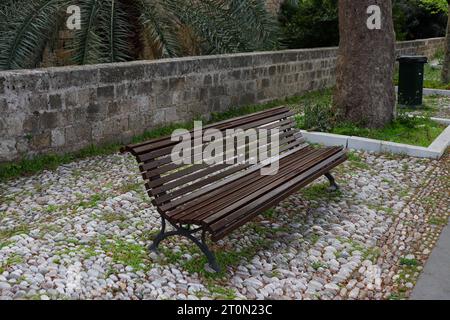 Leere Holzbank im Stadtpark entlang dem Altstadtweg von Rhodos Stockfoto