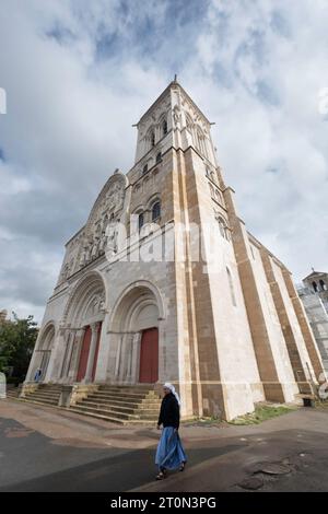 Eine Nonne geht an der Fassade der Benediktiner- und Cluniac-Abteikirche und des Klosters in Vézelay im ostzentralen französischen Departement Yonne vorbei Stockfoto