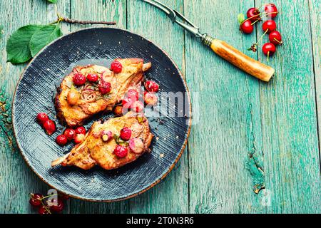 Zwei gekochte Steaks in einer Kirschmarinade. Gebratenes Fleisch mit Beerensauce auf altem Holzhintergrund. Platz für Text Stockfoto