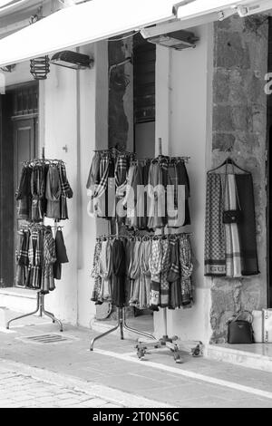 Schals hängen an einem zweilagigen runden Kleiderständer, der in den Geschäften der Altstadt von Rhodos in Schwarz-weiß ausgestellt wird Stockfoto