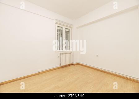 Schlafzimmer eines leeren Hauses mit Laminatboden, Aluminiumfenster mit Gittern und einem Heizkörper darunter Stockfoto