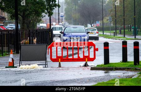 Dundee, Tayside, Schottland, Großbritannien. Oktober 2023. Wetter in Großbritannien: Die Überschwemmungen auf der MacAlpine Road in Ardler Village sind das Ergebnis von nächtlichen sintflutartigen Regenfällen in Dundee. Regen hat die Reise in Dundee beeinflusst und einige Busse aufgrund überfluteter Straßen gezwungen, umzuleiten. Autofahrer werden durch überflutete Straßen gefahren, wodurch Wasser außergewöhnlich hoch spritzt. Quelle: Dundee Photographics/Alamy Live News Stockfoto