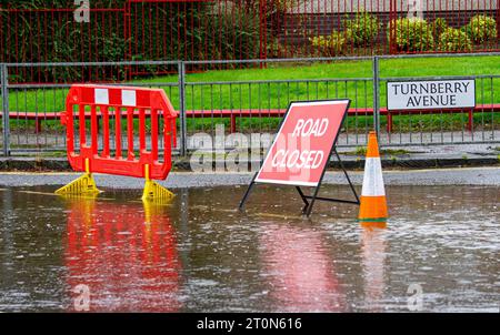 Dundee, Tayside, Schottland, Großbritannien. Oktober 2023. Wetter in Großbritannien: Die Überschwemmungen auf der MacAlpine Road in Ardler Village sind das Ergebnis von nächtlichen sintflutartigen Regenfällen in Dundee. Regen hat die Reise in Dundee beeinflusst und einige Busse aufgrund überfluteter Straßen gezwungen, umzuleiten. Autofahrer werden durch überflutete Straßen gefahren, wodurch Wasser außergewöhnlich hoch spritzt. Quelle: Dundee Photographics/Alamy Live News Stockfoto