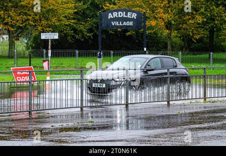 Dundee, Tayside, Schottland, Großbritannien. Oktober 2023. Wetter in Großbritannien: Die Überschwemmungen auf der MacAlpine Road in Ardler Village sind das Ergebnis von nächtlichen sintflutartigen Regenfällen in Dundee. Regen hat die Reise in Dundee beeinflusst und einige Busse aufgrund überfluteter Straßen gezwungen, umzuleiten. Autofahrer werden durch überflutete Straßen gefahren, wodurch Wasser außergewöhnlich hoch spritzt. Quelle: Dundee Photographics/Alamy Live News Stockfoto