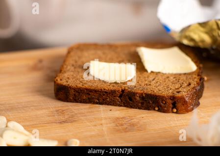 Ein Stück Schwarzbrot mit Butterscheiben auf hölzernem Hintergrund Stockfoto