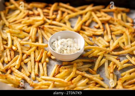 Frisch zubereitete Pommes Frites liegen vor dem Ofen und Soße für sie mit Kräutern Stockfoto