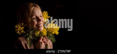 Eine Frau findet Trost in einem Blumenstrauß aus gelben Blumen, selbst in einem dunklen Raum. Banner, Platz für Text Stockfoto