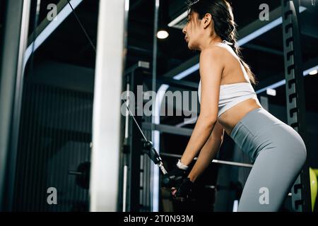 Schlanke und starke junge Frau, die auf einem Pull-down-Gerät arbeitet Stockfoto