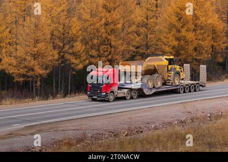 Transport defekter schwerer Geräte auf einer Plattform zum Transport. Nahaufnahme. Herbststraße. Stockfoto