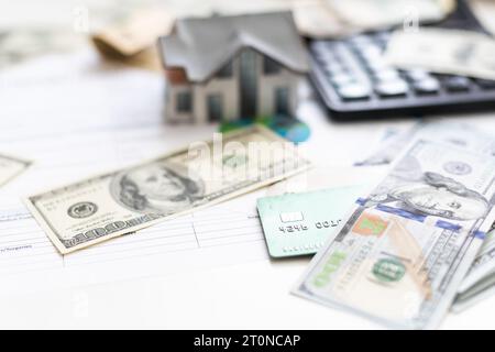 Buchhalter, der an Einkommensteuerformularen oder Budgetplanung mit Währungsnotizen, Taschenrechner und Haus-3D-Modell arbeitet Stockfoto