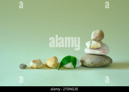 Spa-Steine mit grünem Blatt auf grünem Hintergrund, Meditation, Harmonie, Yoga, Wellnesskonzept, kostenloser Kopierraum Stockfoto