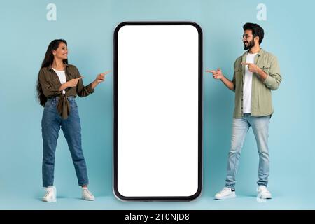 Positives Millennials-hindu-Paar, das mit Mockup auf das Telefon zeigt Stockfoto