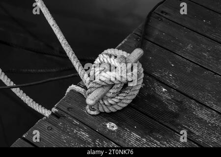 Schwarz-weißer Schiffspoller, der ein Segelboot mit verdrehtem Polyesterseil verankert Stockfoto