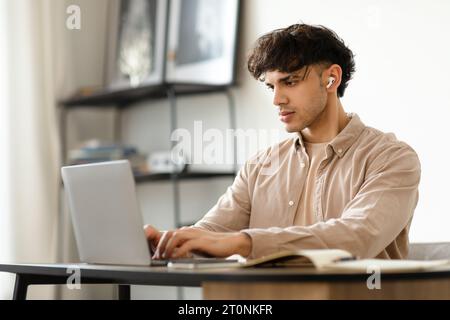 Büroangestellter, Der An Laptop-Schreibtischern Arbeitet Und Ohrstöpsel Am Arbeitsplatz Trägt Stockfoto