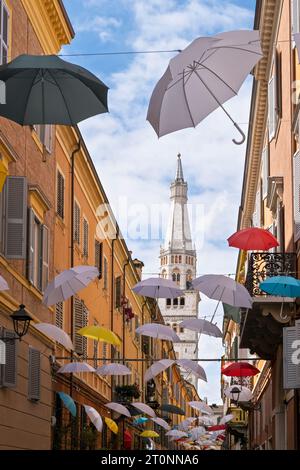 Bunte Regenschirme hängen in einer engen Straße, Ghirlandina, der Glockenturm der Kathedrale von Modena, im Hintergrund. Emilia-Romagna, Italien, Europa Stockfoto