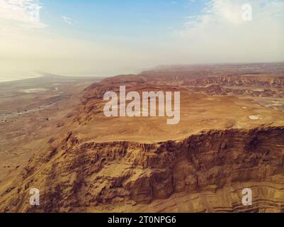 Malerischer Blick auf den Canyon vom Gipfel des Masada-Nationalparks. Felsplateau vor bewölktem Himmel und die Küste des Toten Meeres im Hintergrund. Panorama von m Stockfoto