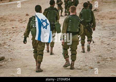 Rückaufnahme mehrerer Soldaten der israelischen Armee, die mit einer israelischen Nationalflagge unterwegs sind. Militärmann, der mit anderen Soldaten läuft. Kriegstaktische Übung. In Stockfoto