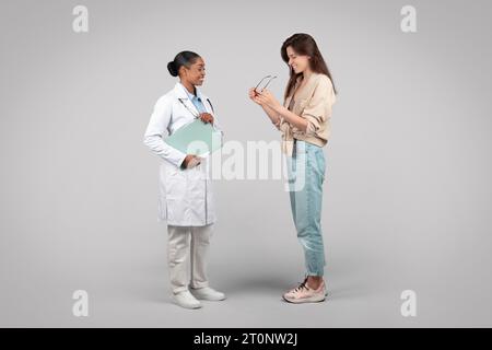 Schwarze Augenärztin hilft Patienten mit Brille Stockfoto