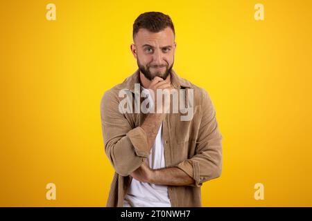 Fröhlicher nachdenklicher, listiger tausendjähriger kaukasier mit Bart in lockeren Gedanken Stockfoto