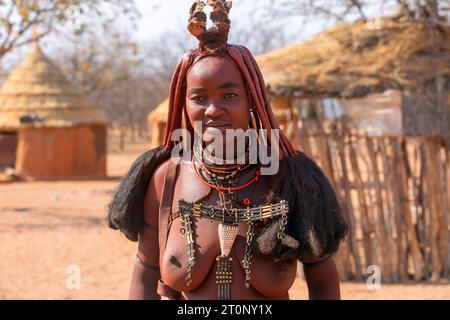 Ländliches Namibia - 22. August 2023. Eine junge Afrikanerin trägt die traditionelle Frisur, Lederketten und ockerfarbene Hautpaste des Himba tr Stockfoto