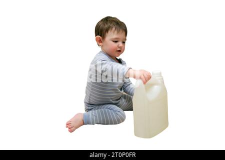 Ein Kind spielt mit chemischen Reinigungsprodukten unter dem Waschbecken in der Küche, isoliert auf weißem Hintergrund. Das Baby hält Flaschen mit Waschmittel. Kind Stockfoto