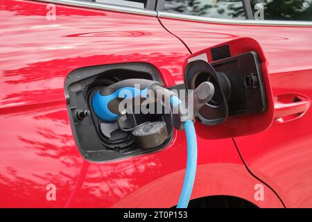 Aufladen des roten Elektrofahrzeugs – Nahaufnahme des Ladegeräts. Stockfoto