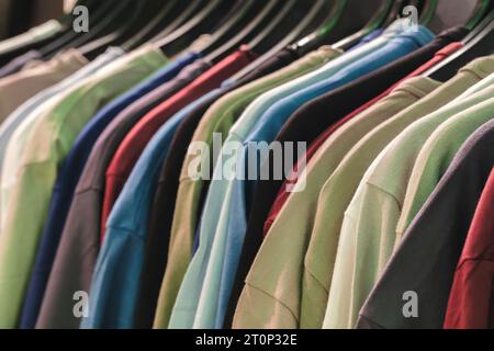 Eine Reihe von neuen, frischen Baumwoll-T-Shirts in bunten Regenbogenfarben hängen im Kleiderschrank auf der Kleiderstange. Stockfoto