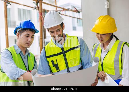 Zufriedene Gruppe von Bauarbeitern, die mit Architekten und Vorarbeiter im Gespräch arbeiten, beraten die Projektplanung mit Grundriss Stockfoto