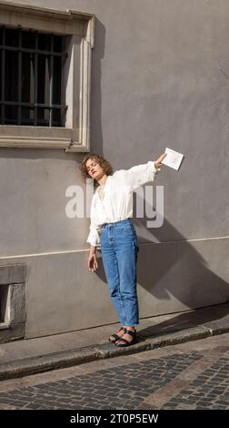 Junge Frau, die sich in der Warschauer Altstadt an eine Mauer lehnt und eine Kopie von Kameliowy Sklep Papierniczy von Ito Ogawa hält Stockfoto