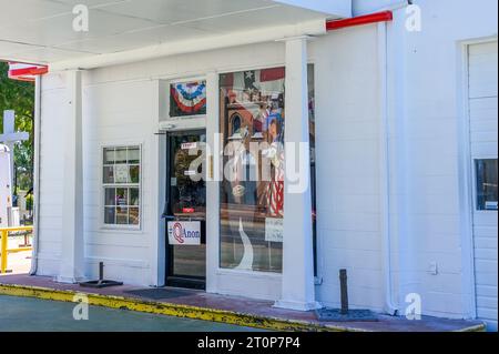 NEW ROADS, LA, USA - 19. SEPTEMBER 2023: Eingang zur Retro-Tankstelle mit Trump-Bild und Stoßfänger-Aufkleber und Qanon-Schild Stockfoto