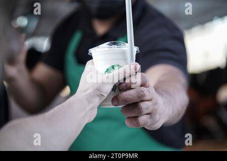 Starbucks-Mitarbeiter geben Bestellungen am Drive-Thru. frappuccino aus Milch. Stockfoto