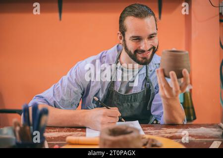 Handwerklicher Töpferkünstler glücklich mit Werkstatt-Prototyp Tontopf Produktionsdesign für handgefertigte Kleinunternehmen Stockfoto