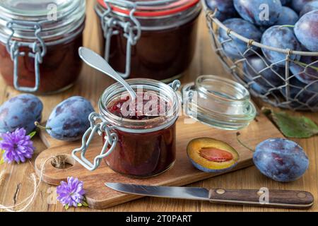 Pflaumenmarmelade in hausgemachtem Glas und frische Pflaumen im Korb Stockfoto