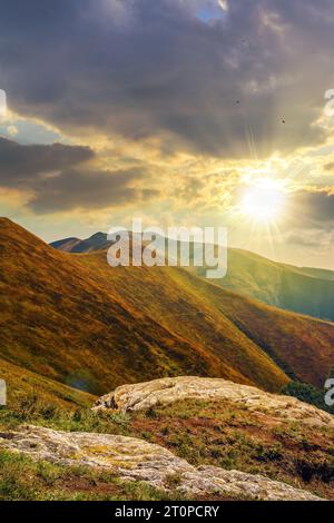 Berglandschaft mit Steinen, die im Gras auf der Hügelseite unter dem bewölkten Sommerhimmel bei Sonnenuntergang liegen. Wunderschöne Landschaft im Hinterland Stockfoto