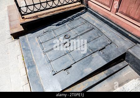 Eine Metallluke im Keller eines alten Hauses. Eingang zum Keller von der Straße Stockfoto