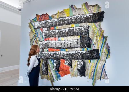 London, Großbritannien. Oktober 2023. LONDON, VEREINIGTES KÖNIGREICH - 06. OKTOBER 2023: Ein Mitarbeiter der Galerie betrachtet ein Gemälde von El Anatsui, Geschicklichkeit, 2019, geschätzte £ 500.000 - 700.000, während eines Fotoanrufs in Sotheby's Auktionshaus, das am 06. Oktober 2023 die Höhepunkte der Frieze Week Sales in London, Großbritannien, zeigt. Die Kunstwerke werden vom 7. Bis 11. Oktober in Sotheby's Auktionshaus zu sehen sein, bevor sie während der Now und Contemporary Evening Auktionen am 12. Oktober angeboten werden. (Foto: Wiktor Szymanowicz/NurPhoto) Credit: NurPhoto SRL/Alamy Live News Stockfoto