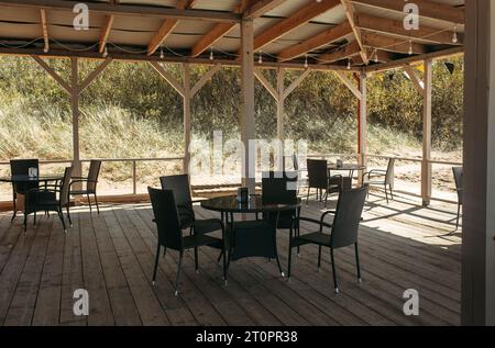 Holztische und -Stühle in einem sonnigen, leeren Restaurant. Stockfoto