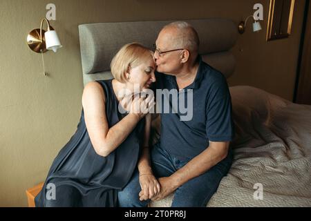 Glückliches älteres Paar. Eine ältere Frau streichelt die Hand ihres Mannes und drückt sanft gegen ihn. Stockfoto