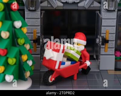 Tambow, Russische Föderation - 08. Oktober 2023 Eine Lego Santa Claus Minifigur schiebt eine Schubkarre voller Geschenke aus einem Gebäude. Nahaufnahme. Stockfoto