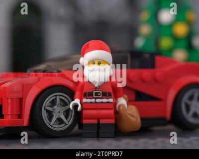 Tambow, Russische Föderation - 08. Oktober 2023 Eine Lego Santa Claus Minifigur, die vor einem Ferrari LaFerrari-Auto steht und einen Sack mit Geschenk hält Stockfoto