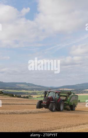 Pressen von Gerstenstroh mit einem Valtra-Traktor und einer McHale-Ballenpresse auf Aberdeenshire Stockfoto